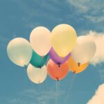 Vibrant balloons floating against a serene blue sky, perfect for celebrations.